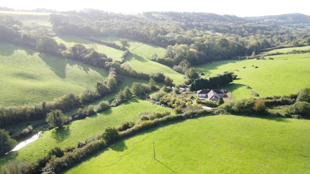 Lot: 26 - SMALL HOLDING OF APPROXIMATELY 86 ACRES OF PASTURE AND WOODLAND, DETACHED BUNGALOW PLUS TWO AGRICULTURAL BARNS - Drone picture of Mincombe farm, land and woodland